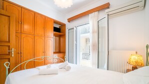 Una habitación de hotel con una cama, un armario de madera, una ventana con cortinas y una lámpara sobre una mesita de noche.