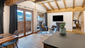 A modern interior with a wooden ceiling, a dining area, a TV mounted on the wall, and a view of the outdoors. - Apartment 'Alpin Chalet Samer Fürstenblick' with Mountain View, Terrace and Wi-Fi (Sarntal)