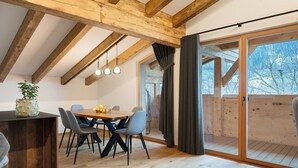 A dining area with a wooden table and chairs, a potted plant, and a view through a glass door to an outdoor deck. - Apartment 'Alpin Chalet Samer Fürstenblick' with Mountain View, Terrace and Wi-Fi (Sarntal)