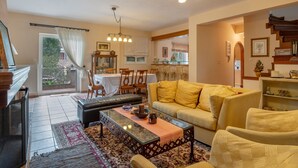 Een woonkamer met een bank, fauteuils, een salontafel en een eethoek met stoelen en een tafel.