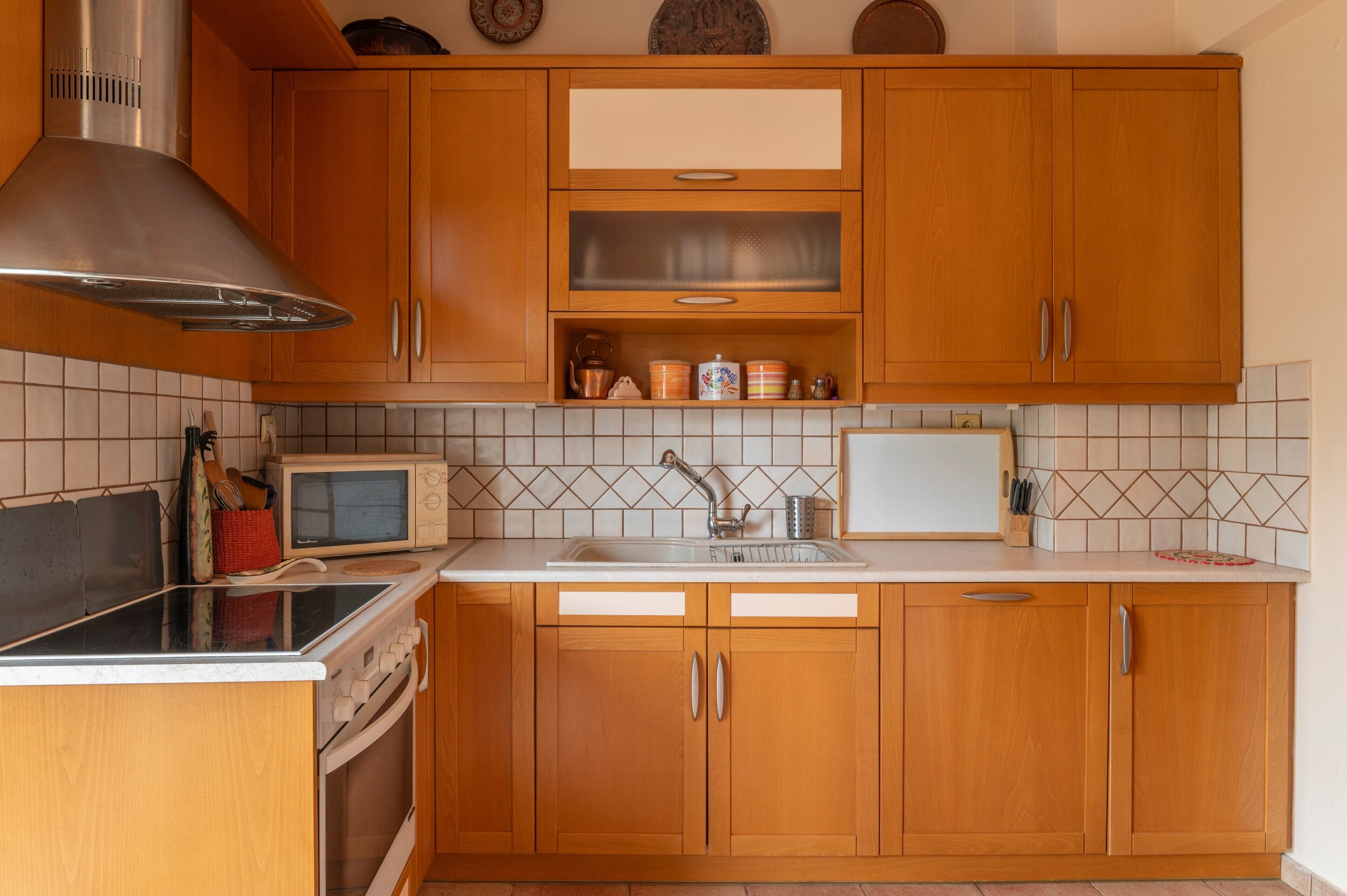 A kitchen with wooden cabinets, a microwave, a stove, and a sink.