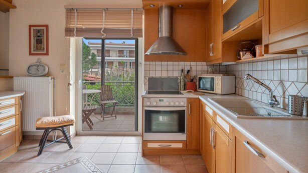 Een keuken met houten kastjes, een fornuis, een magnetron en een groot raam.