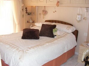 A neatly made bed with a white duvet and two dark brown pillows, a wooden headboard, and a bedside table with a lamp. - Luxury Villa "Violeta" with Sea Views, Private Pool, Terraces, and Wi-Fi (Adeje)