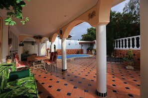 A covered patio with a pool, seating area, and potted plants. - Luxury Villa "Violeta" with Sea Views, Private Pool, Terraces, and Wi-Fi (Adeje)