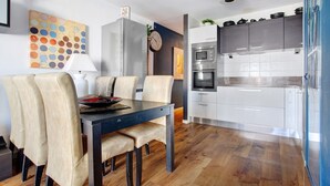 Eine moderne Küche mit weißen Schränken, einem Edelstahlkühlschrank und einer Mikrowelle.