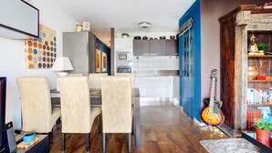 Ein modernes Wohnzimmer mit Essbereich, Küche und einer Gitarre.