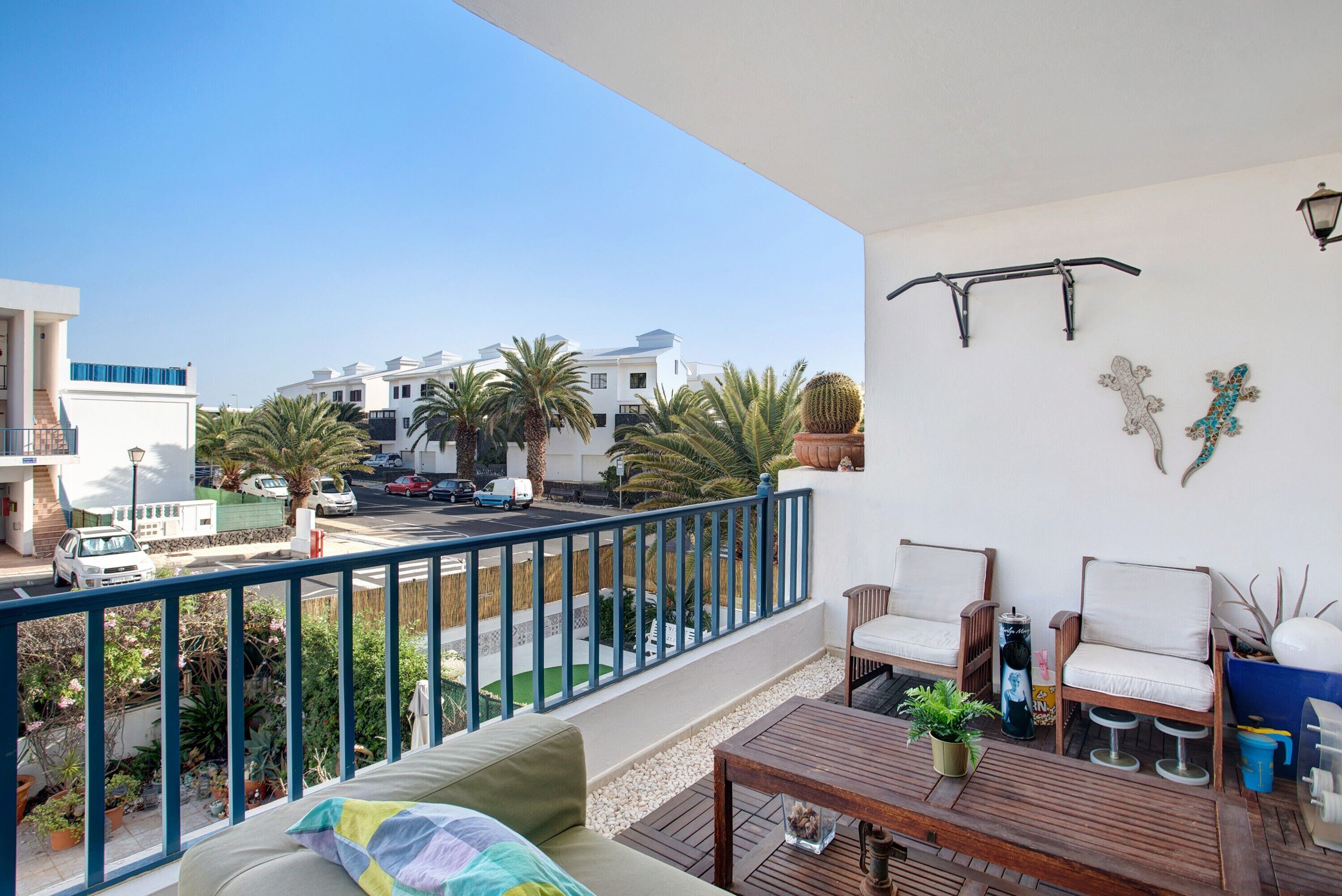 A balcony with a wooden table, two chairs, a sofa, and a railing.