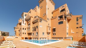 Hotel de diverses plantes amb piscina, balcons i un cel blau clar.