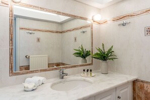 Un baño con un espejo grande, un lavamanos y dos plantas en macetas.