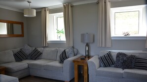 Ein Wohnzimmer mit zwei grauen Sofas, einem Holztisch und einer Stehlampe.