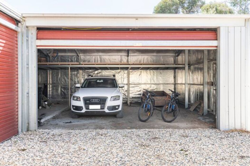 A garage with a white Audi car and two bicycles inside.