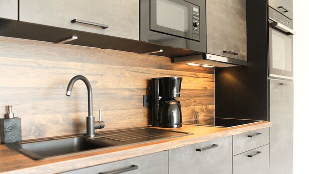 Une cuisine moderne dotée d’un plan de travail en bois, d’un évier en acier inoxydable et d’une machine à café.