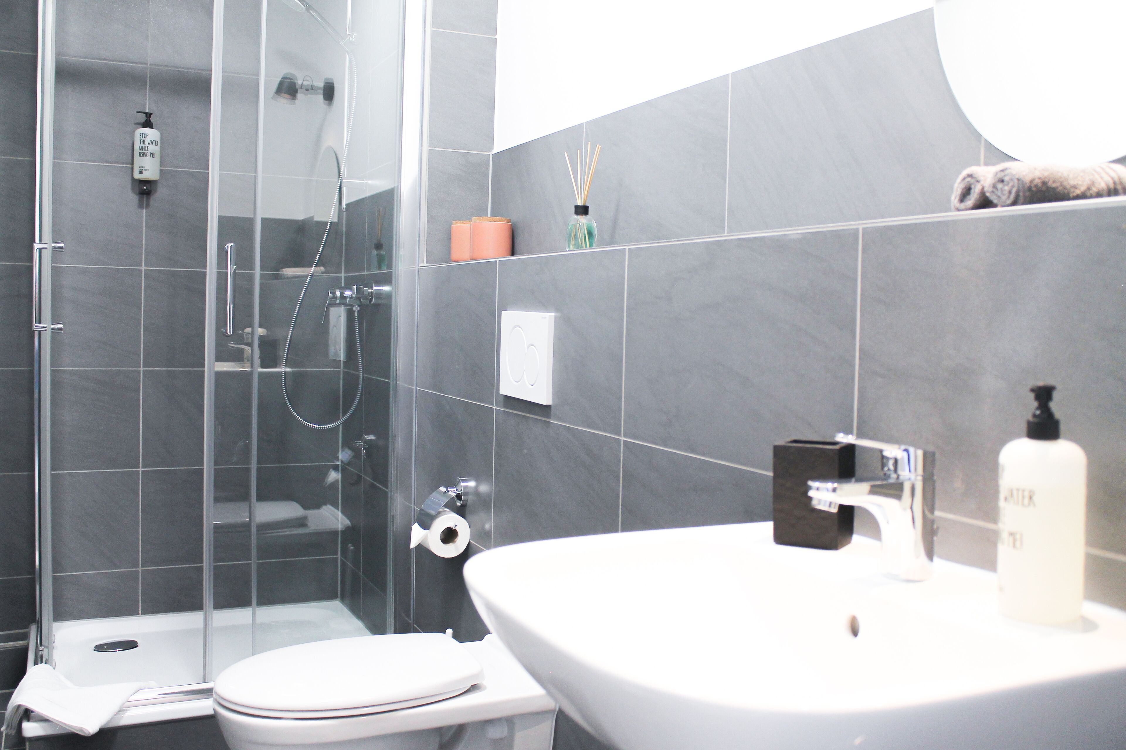 A modern bathroom with a glass-enclosed shower, a white sink, and a toilet.