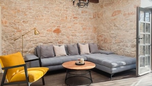 A cozy living room with a stone wall, a gray sectional sofa, a yellow chair, and a round coffee table.