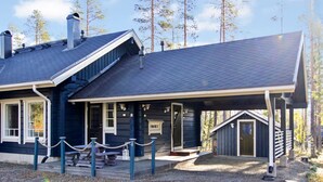Eine Lodge mit überdachter Veranda, Kamin und einer Terrassenfläche.