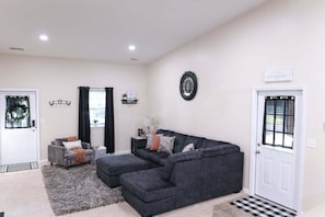 A living room with a sectional sofa, a small table, and a door with a window. - Quiet Indiana Getaway w/ Game Room (Moores Hill)