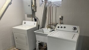 A laundry area with two washing machines, a sink, and visible plumbing. - Cozy Detroit home in the Center of Metro Detroit. (Detroit)