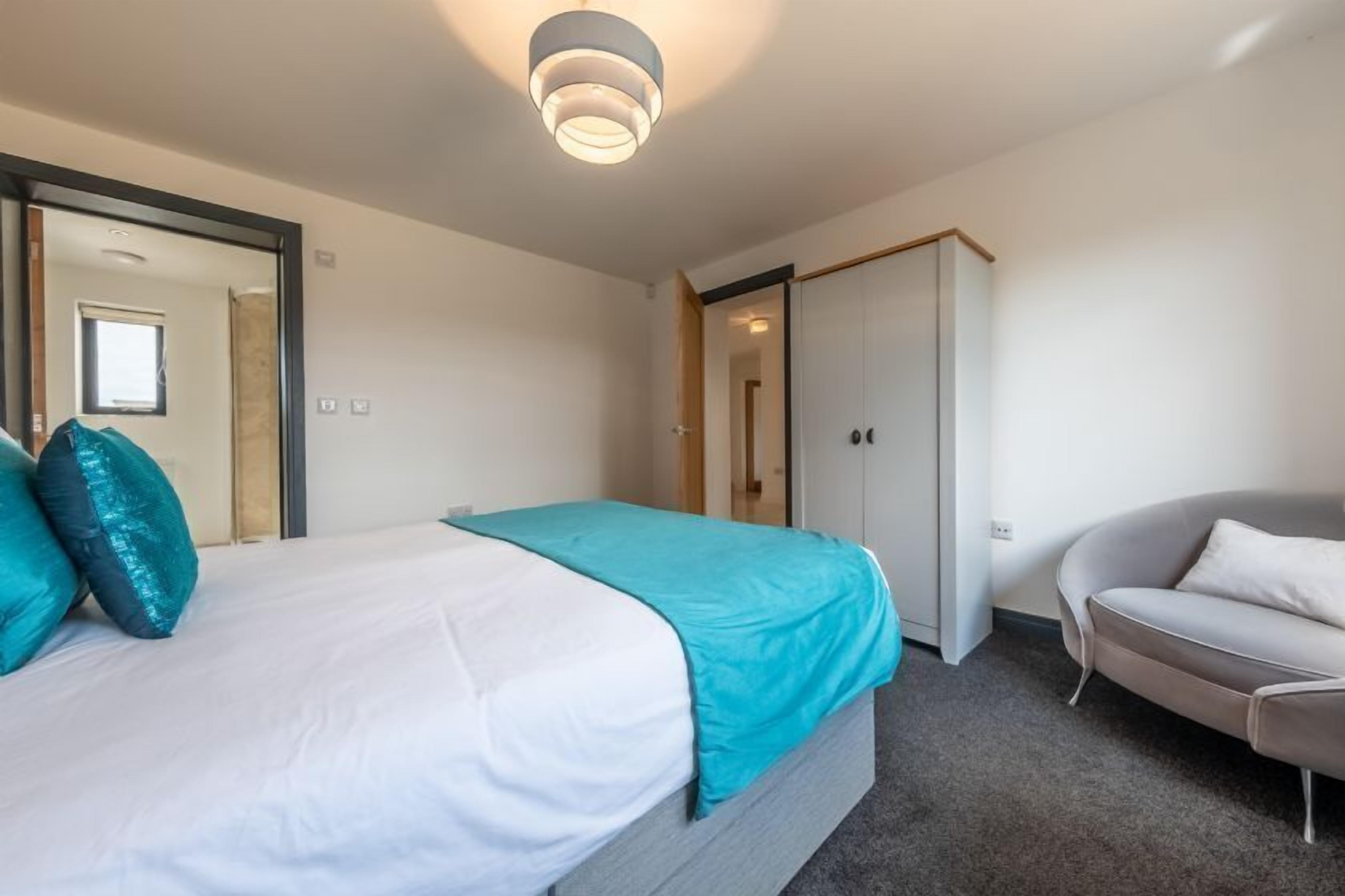 A bedroom with a bed, a grey sofa, and a wardrobe.