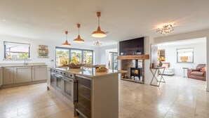 Cozinha espaçosa com ilha central, eletrodomésticos de aço inoxidável e iluminação pendente.