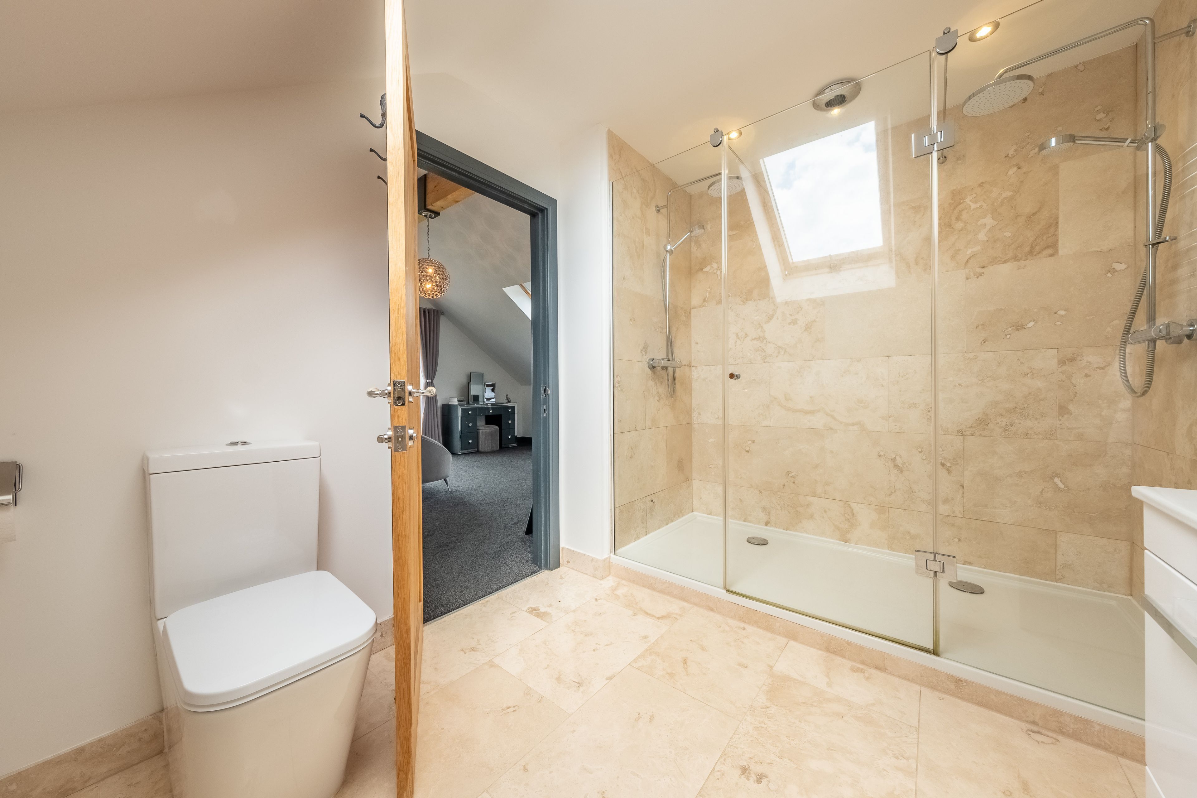 Et moderne badeværelse med et glasafskærmet brusebad, toilet og håndvask.