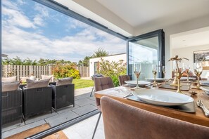 A dining area with a table set for four, outdoor furniture, and a view of the backyard. - Wynholme, Holme-next-the-Sea, Norfolk (Holme-next-the-Sea)