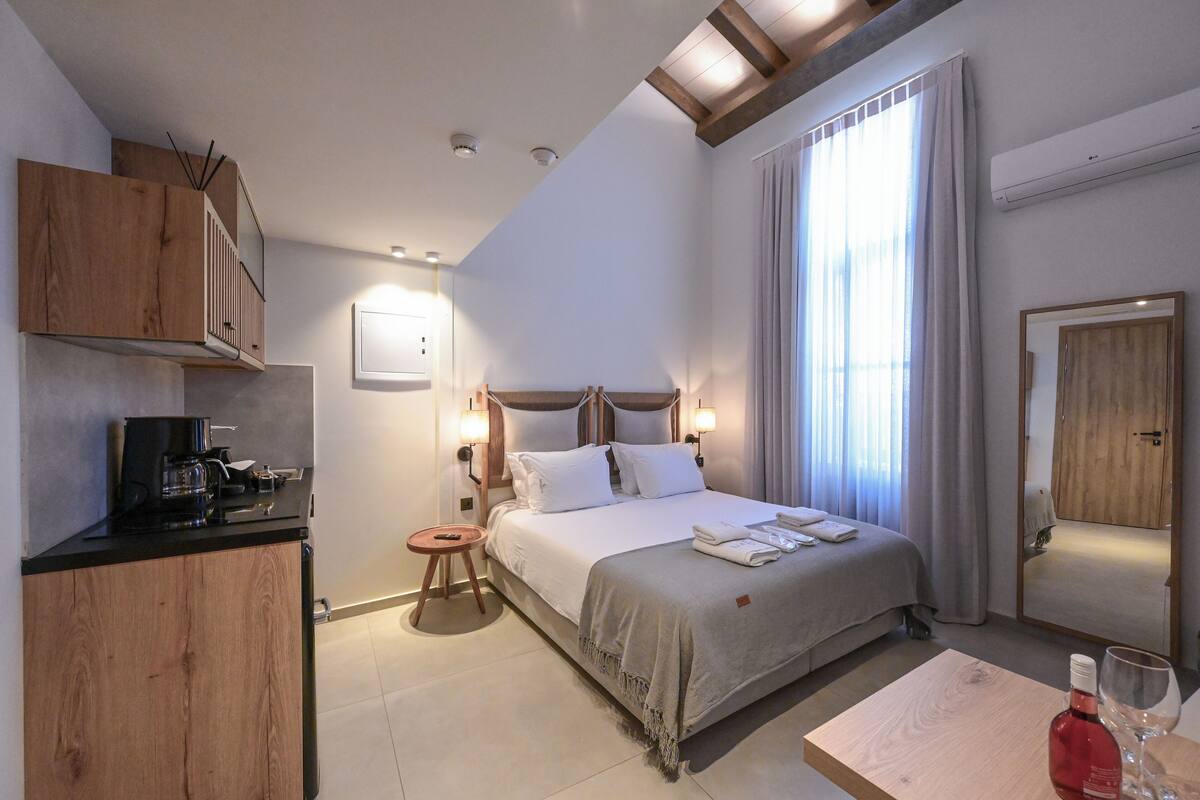 A hotel room with a bed, bedside table, and a kitchenette area.
