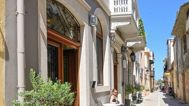 A boutique hotel named MAREA with a sign above the entrance, a narrow street, and a person sitting at an outdoor table. - Marea Boutique Suites (Rethymno)