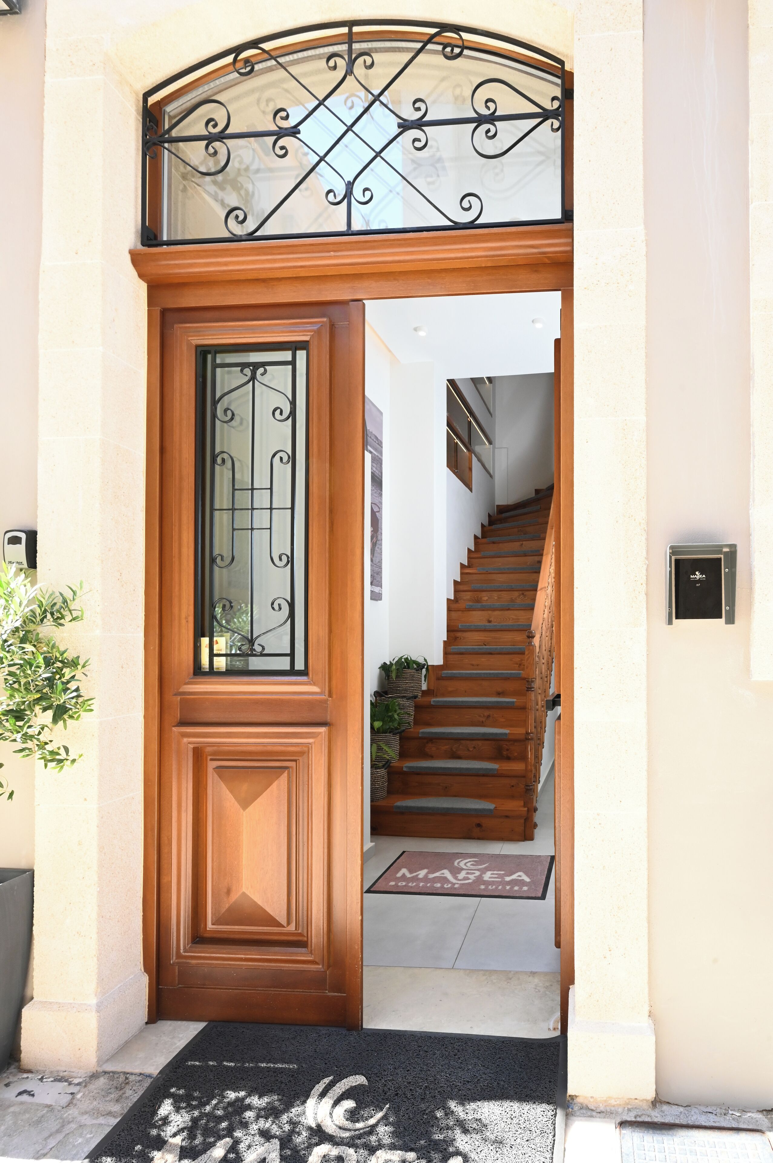 A wooden door with a glass panel and a metal decorative arch above it.