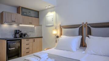 Ein Hotelzimmer mit Bett, einer kleinen Küchenzeile, einem Fernseher und einem Nachttisch.