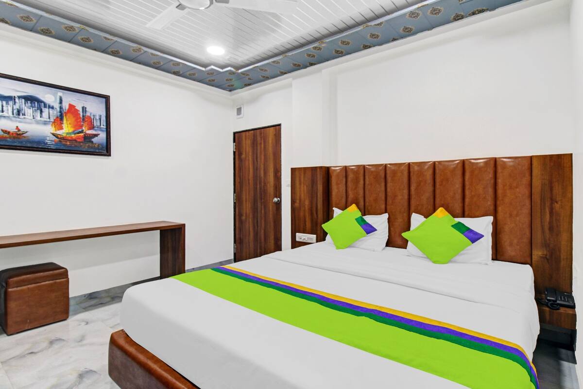 Quarto de hotel com uma cama, uma escrivaninha e uma cadeira.