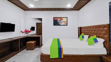 A modern bedroom with a wooden headboard, a flat-screen TV, a mirror, and a colorful painting on the wall.