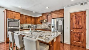 Una cocina con armarios de madera, electrodomésticos de acero inoxidable y encimera de granito.