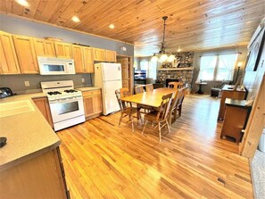 A kitchen with wooden cabinets, a stove, a microwave, and a dining table with chairs.