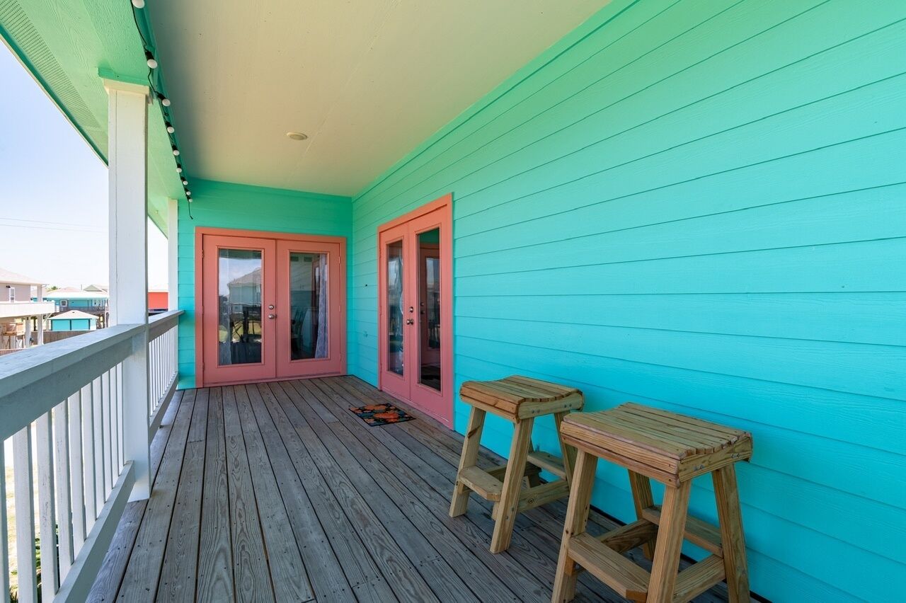 Eine Holzterrasse mit einer türkisblauen Wand und einer roten Tür.