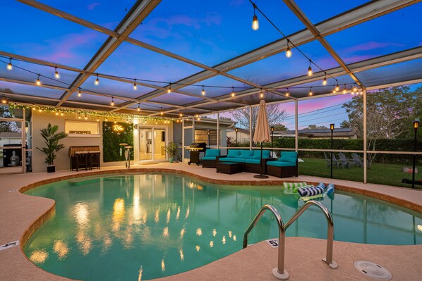 Heated, saltwater pool oasis with relaxing lighting, furniture, and bbq grill.
