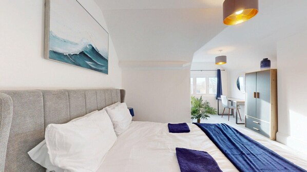 A modern hotel room with a large bed, a desk, and a view of the city. - Stylish Georgian Apartment In An Ideal Location (North Walsham)