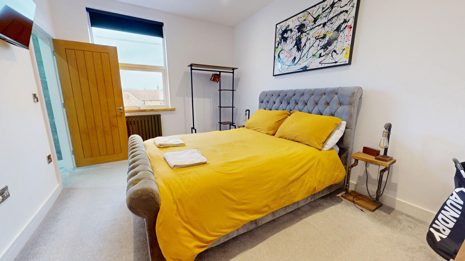 Une chambre à coucher avec un lit, une fenêtre, un radiateur, une échelle, un tableau et un sac.