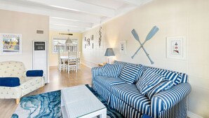 A living room with a striped sofa, a patterned armchair, and a glass coffee table. - Sunny Rio Del Mar Beach Townhome – Relax, Unwind & Enjoy the Coast (Aptos)