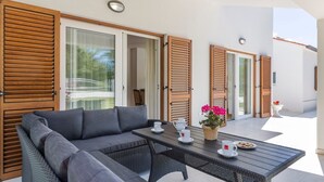 A modern outdoor seating area with a sofa and table, wooden shutters, and a view of the street. - Charming Villa Ana with a swimming pool (Labin)