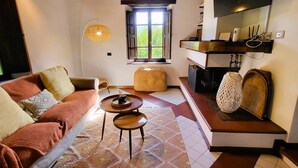 A cozy living room with a sofa, two side tables, a woven pouf, and a window with a view. - Beautifully converted watermill with private pool and own waterfall! (San Romano in Garfagnana)