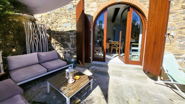 A stone building with an open wooden door leading to a dining area. - Beautifully converted watermill with private pool and own waterfall! (San Romano in Garfagnana)