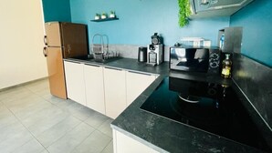 Eine moderne Küche mit schwarzem Arbeitsplatz, Edelstahlgeräten und tealfarbenen Wänden.