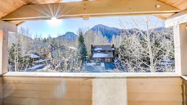 A wooden cabin with a view of snow-covered mountains and houses.