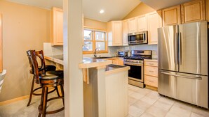 A kitchen with wooden cabinets, a stainless steel refrigerator, a microwave, and a stove.