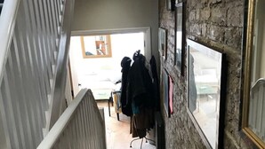 Una escalera de madera que lleva a una habitación con pared de ladrillo y un perchero.