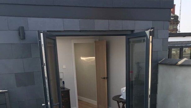 Un apartamento moderno con un cerramiento de vidrio corredero que da a una terraza de madera.
