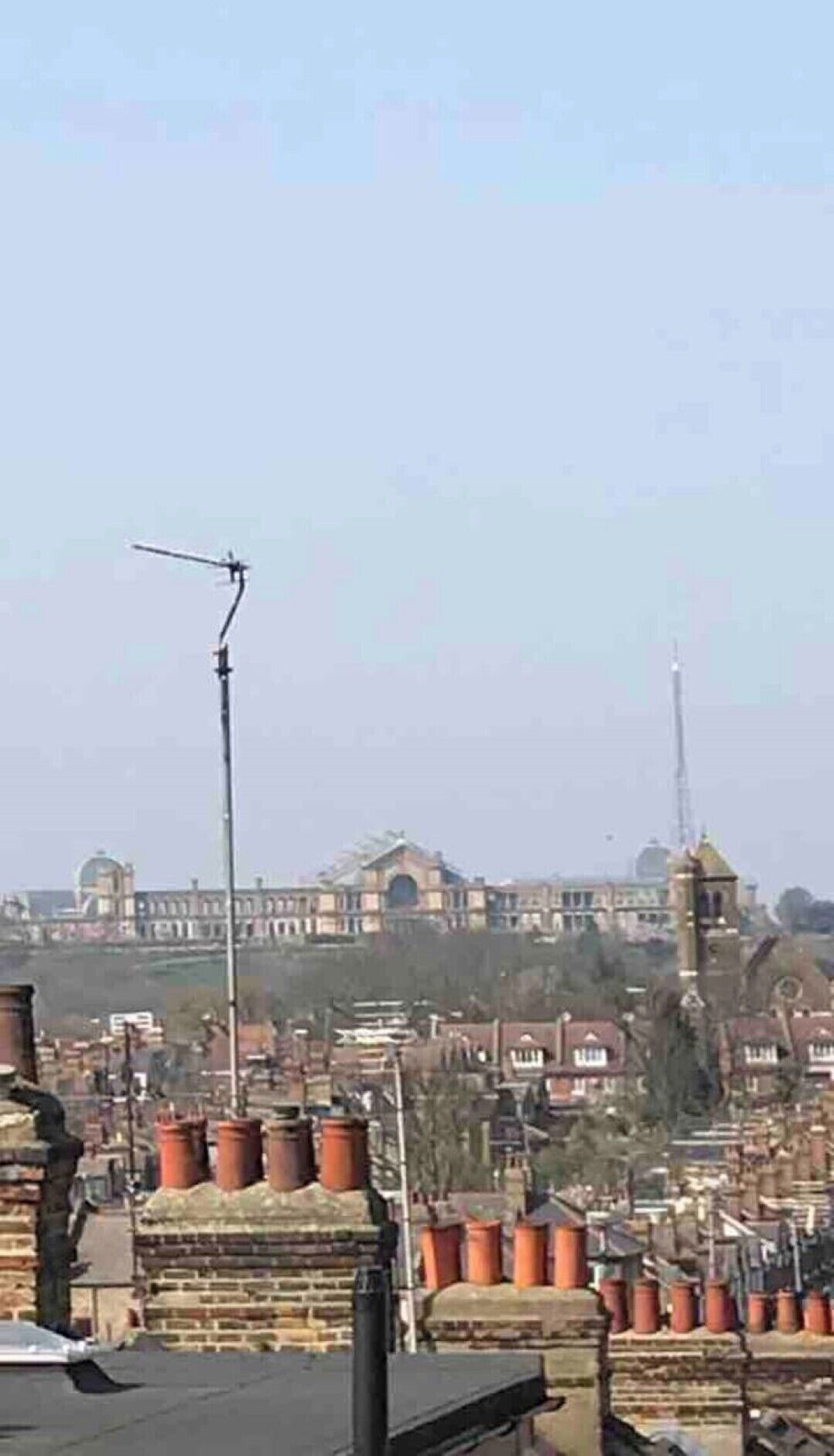 A cityscape with a prominent tower and a large building with domes in the background.