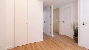 Un couloir avec des portes blanches, un plancher en bois et une plante dans un panier.