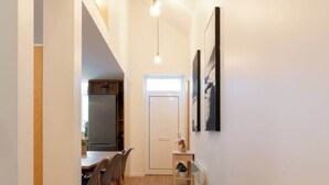Un couloir avec un plancher en bois, un coin repas avec des chaises, un réfrigérateur et une cuisine équipée d  ’un évier et d’un plan de travail.