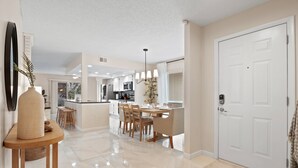 A modern kitchen with white cabinets, a central island, and a dining area with wooden chairs and a table.